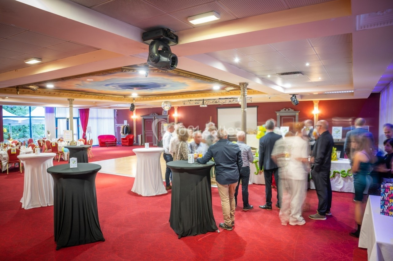 Anniversaire au Salon Impérial Personnes rassemblées dans une salle de réception avec tables hautes, éclairage chaleureux et décorations élégantes.