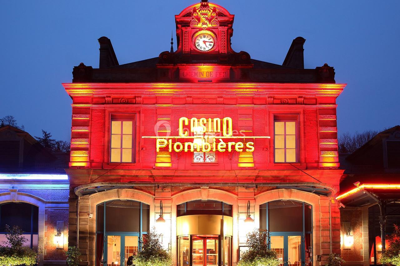 Façade illuminée du casino de Plombières-les-Bains avec horloge centrale et enseigne lumineuse.