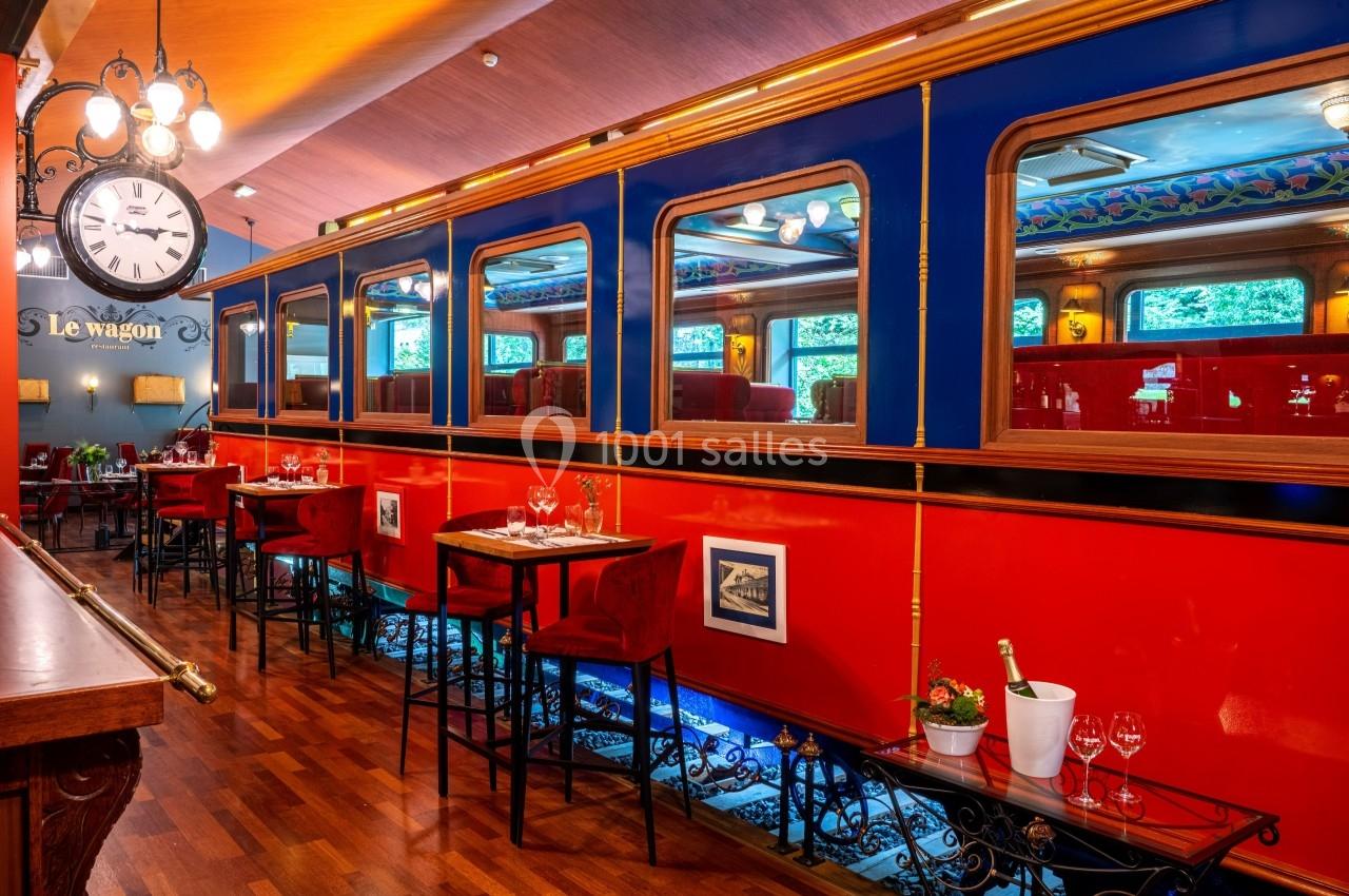 Salle de restaurant décorée comme un wagon de train, avec tables dressées et ambiance chaleureuse.