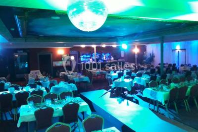 Un barman réalise un spectacle de flair bartending avec des verres et un shaker dans une salle éclairée.