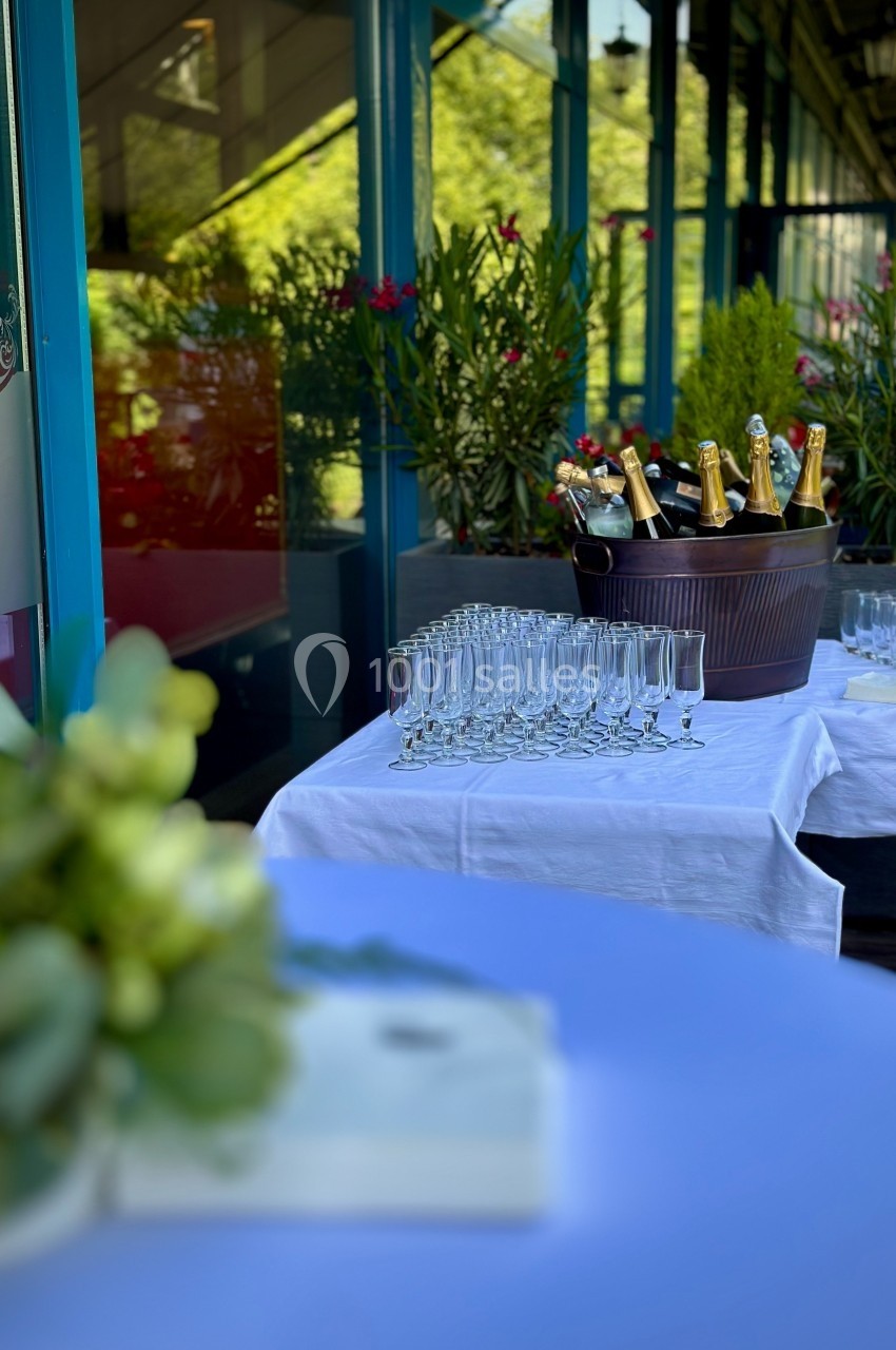 Prêt pour un moment privilégié sur la terrasse Seau rempli de bouteilles de champagne avec des flûtes alignées sur une table blanche en extérieur.