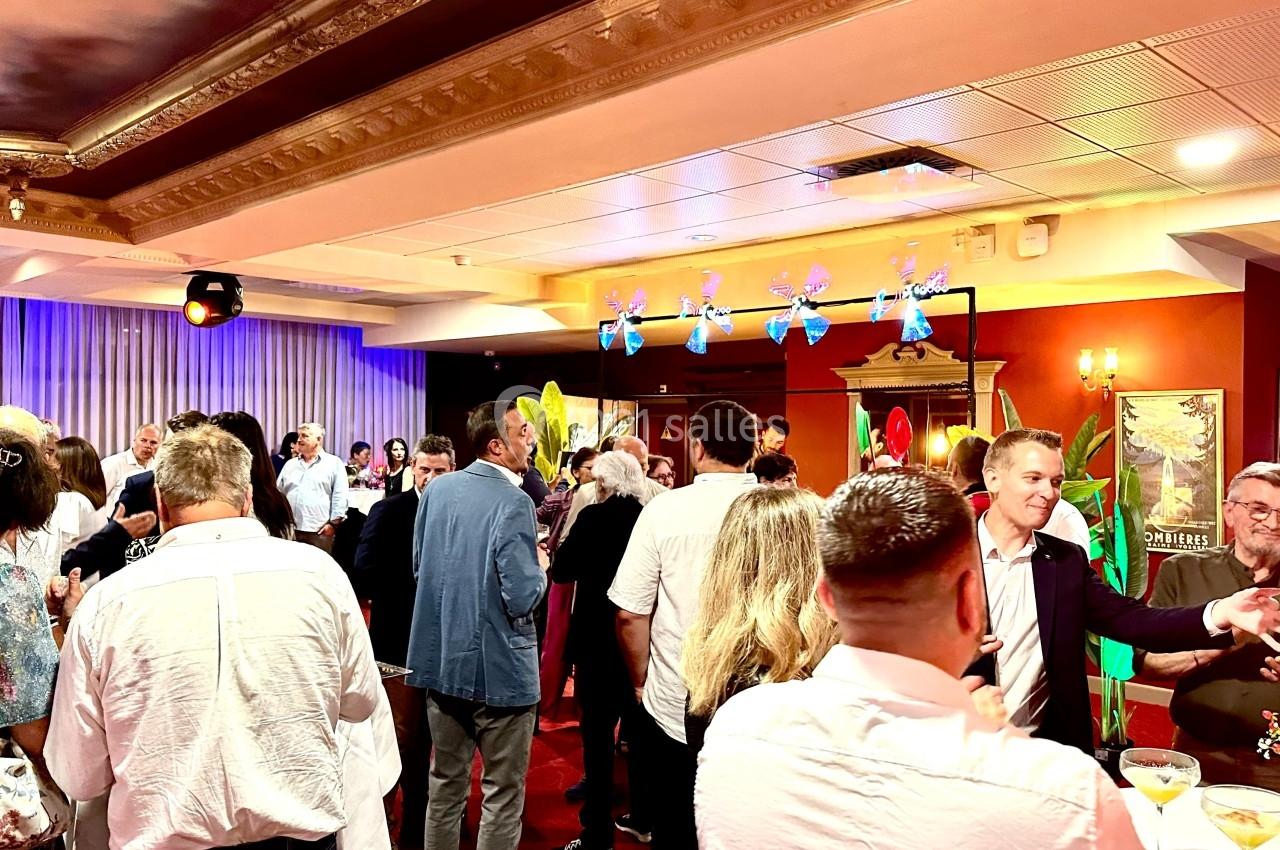 Groupe de personnes rassemblées dans une salle décorée, discutant lors d'un événement ou d'une réception.