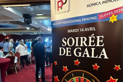 Miniature Soirée de gala au Salon Impérial Bâtiment en briques rouges avec horloge, entouré de verdure, situé près d'un ruisseau et d'une pente herbeuse.