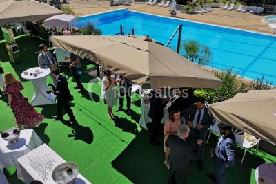 Façade d'un bâtiment avec l'inscription ’Casino’, terrasse animée, parasols blancs et piscine en contrebas.