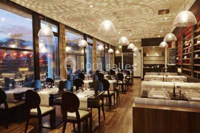 Façade d'un bâtiment avec l'inscription ’Casino’, terrasse animée, parasols blancs et piscine en contrebas.