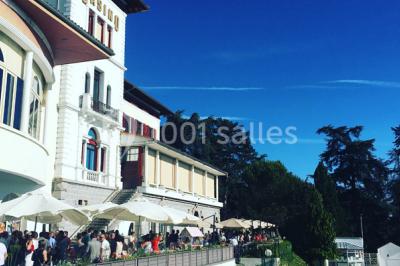 Façade d'un bâtiment avec l'inscription ’Casino’, terrasse animée, parasols blancs et piscine en contrebas.
