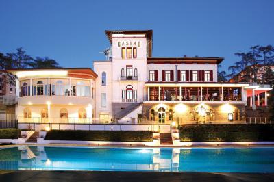 Façade d'un bâtiment avec l'inscription ’Casino’, terrasse animée, parasols blancs et piscine en contrebas.