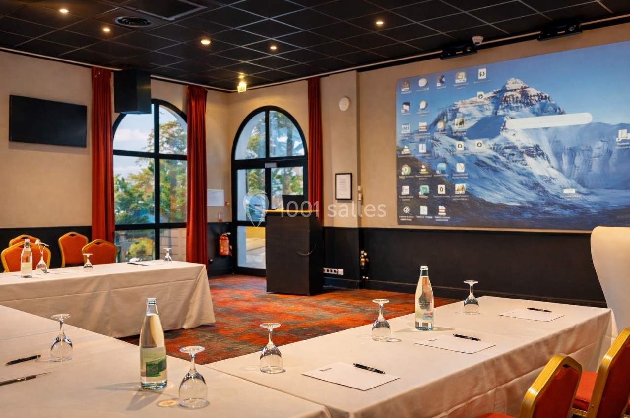 Location salle Saint-Galmier (Loire) - Casino de Saint-Galmier #2 Salle de conférence équipée de tables, chaises, bouteilles d'eau, et écran de projection affichant un bureau d'ordinateur.