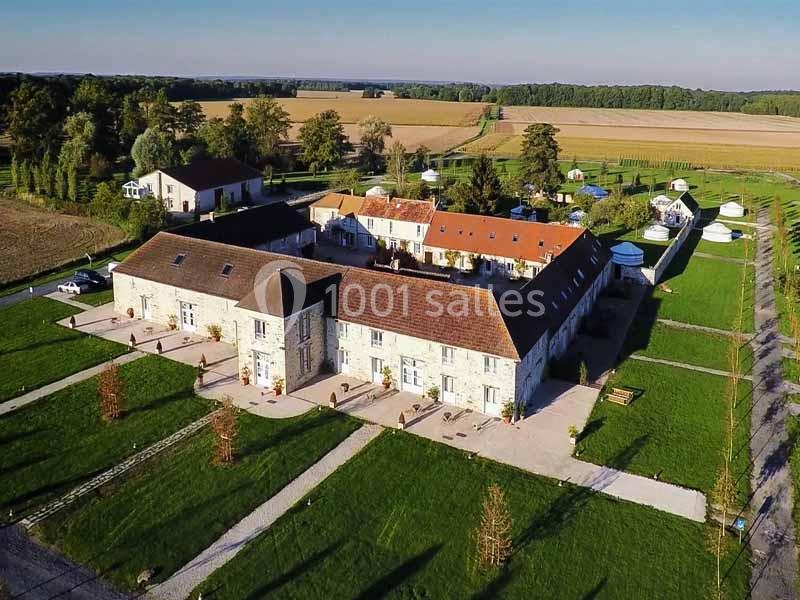Vue aérienne d'un domaine rural avec bâtiments en pierre, toits en tuiles et espaces verts environnants.