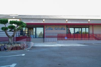 Façade d'une salle de réception avec une entrée accessible et un parking devant.