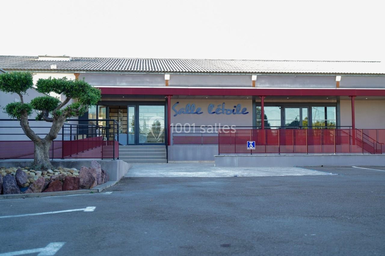 Façade d'une salle de réception avec une entrée accessible et un parking devant.