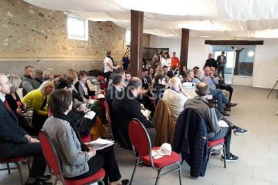 Lit double avec une couverture colorée, deux oreillers, tables de chevet en bois et une lampe dans une chambre simple.