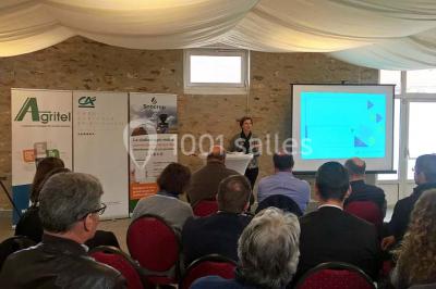 Lit double avec une couverture colorée, deux oreillers, tables de chevet en bois et une lampe dans une chambre simple.