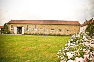 Lit double avec une couverture colorée, deux oreillers, tables de chevet en bois et une lampe dans une chambre simple.