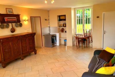 Lit double avec une couverture colorée, deux oreillers, tables de chevet en bois et une lampe dans une chambre simple.