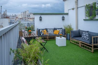 Salle lumineuse avec parquet, plafond décoré de ballons dorés, table avec plantes et vue sur des bâtiments urbains.