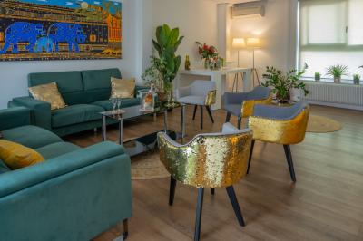 Salle lumineuse avec parquet, plafond décoré de ballons dorés, table avec plantes et vue sur des bâtiments urbains.
