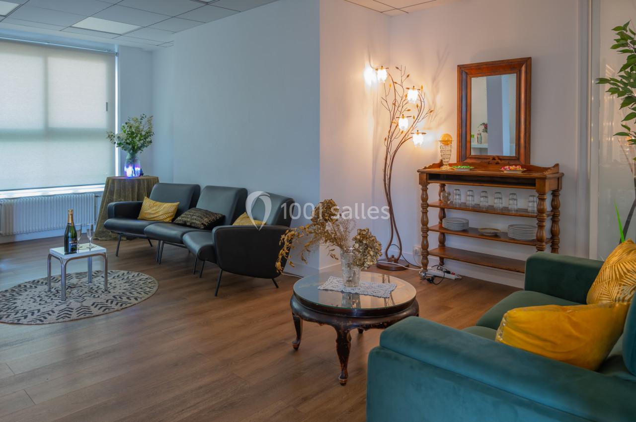 Salon lumineux avec canapés, table basse, miroir, étagère en bois et décoration florale dans un cadre chaleureux.