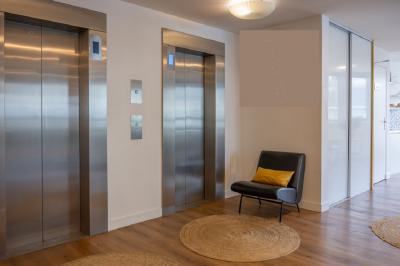 Salle lumineuse avec parquet, plafond décoré de ballons dorés, table avec plantes et vue sur des bâtiments urbains.