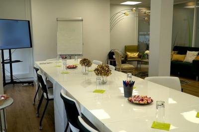 Salle lumineuse avec parquet, plafond décoré de ballons dorés, table avec plantes et vue sur des bâtiments urbains.
