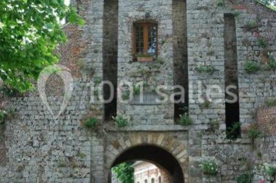 Des bancs en bois disposés en extérieur, entourés de décorations végétales, avec des arbres et des bâtiments en arrière-plan.