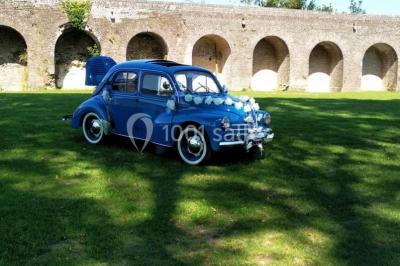 Des bancs en bois disposés en extérieur, entourés de décorations végétales, avec des arbres et des bâtiments en arrière-plan.