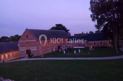 Des bancs en bois disposés en extérieur, entourés de décorations végétales, avec des arbres et des bâtiments en arrière-plan.