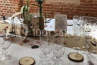 Des bancs en bois disposés en extérieur, entourés de décorations végétales, avec des arbres et des bâtiments en arrière-plan.