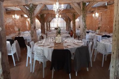 Des bancs en bois disposés en extérieur, entourés de décorations végétales, avec des arbres et des bâtiments en arrière-plan.