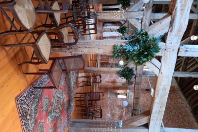 Des bancs en bois disposés en extérieur, entourés de décorations végétales, avec des arbres et des bâtiments en arrière-plan.