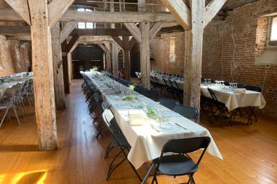 Des bancs en bois disposés en extérieur, entourés de décorations végétales, avec des arbres et des bâtiments en arrière-plan.