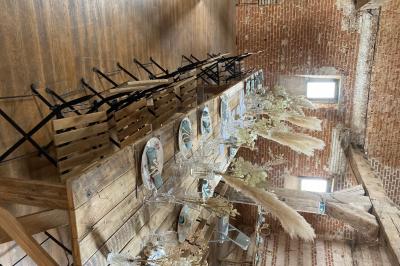 Des bancs en bois disposés en extérieur, entourés de décorations végétales, avec des arbres et des bâtiments en arrière-plan.