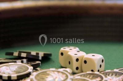 Des jetons de casino et deux dés blancs posés sur une table de jeu verte.