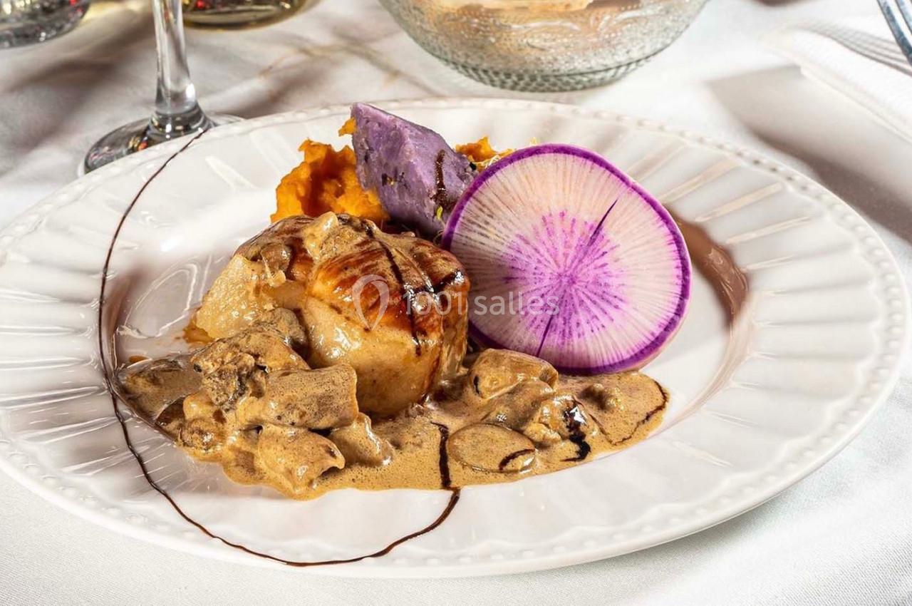 Assiette gastronomique avec viande en sauce, purées colorées, tranche de radis violet et décoration de sauce.