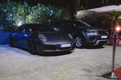 Deux voitures de luxe, une sportive grise et un SUV gris foncé, stationnées côte à côte en extérieur de nuit.