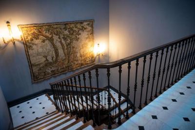 Salle de bain avec carrelage bleu et blanc à motifs, deux lavabos, un miroir et une fenêtre avec rideaux blancs.