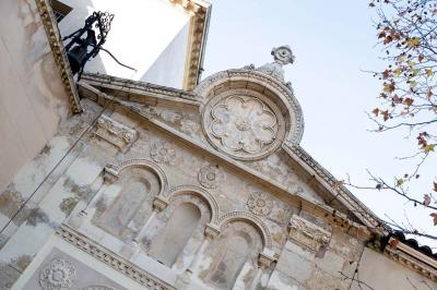 Salle de bain avec carrelage bleu et blanc à motifs, deux lavabos, un miroir et une fenêtre avec rideaux blancs.