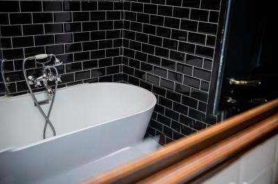 Salle de bain avec carrelage bleu et blanc à motifs, deux lavabos, un miroir et une fenêtre avec rideaux blancs.