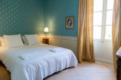 Salle de bain avec carrelage bleu et blanc à motifs, deux lavabos, un miroir et une fenêtre avec rideaux blancs.