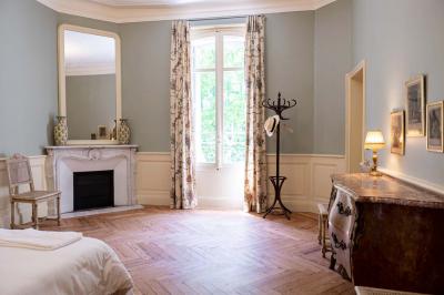 Salle de bain avec carrelage bleu et blanc à motifs, deux lavabos, un miroir et une fenêtre avec rideaux blancs.