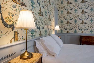 Salle de bain avec carrelage bleu et blanc à motifs, deux lavabos, un miroir et une fenêtre avec rideaux blancs.