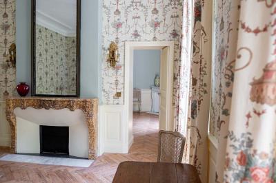 Salle de bain avec carrelage bleu et blanc à motifs, deux lavabos, un miroir et une fenêtre avec rideaux blancs.