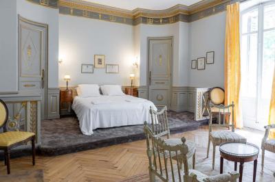 Salle de bain avec carrelage bleu et blanc à motifs, deux lavabos, un miroir et une fenêtre avec rideaux blancs.