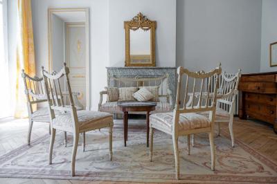 Salle de bain avec carrelage bleu et blanc à motifs, deux lavabos, un miroir et une fenêtre avec rideaux blancs.