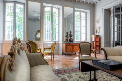 Salle de bain avec carrelage bleu et blanc à motifs, deux lavabos, un miroir et une fenêtre avec rideaux blancs.
