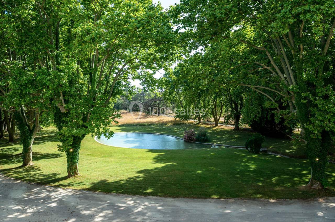 Étang entouré de pelouse et d'arbres verdoyants sous un ciel dégagé.