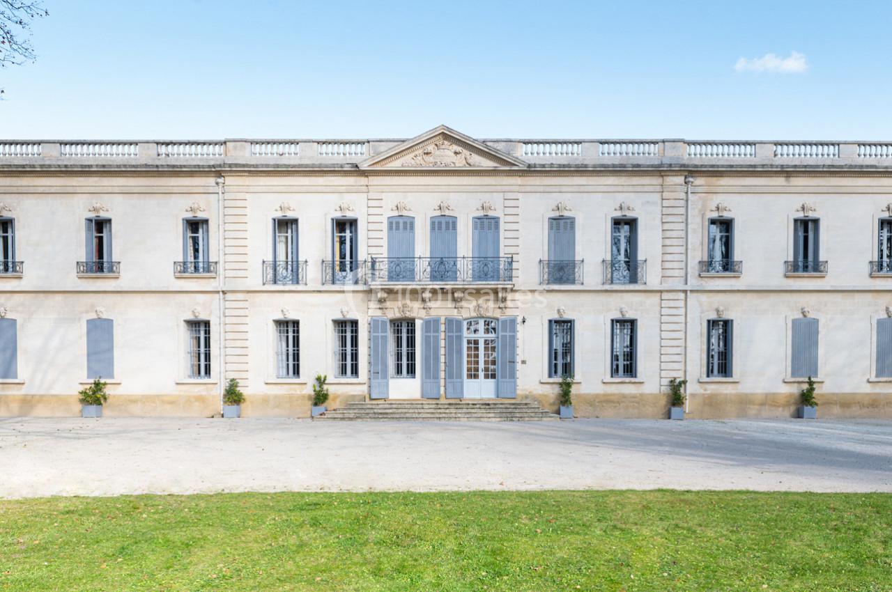 Façade d'un bâtiment historique avec des volets bleus, balcons en fer forgé et une entrée centrale monumentale.