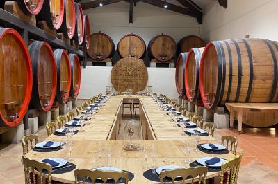 Une voiture bleue traverse un chemin bordé de vignes et de murets en pierre sous un ciel dégagé.