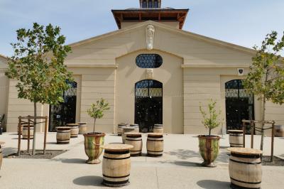 Une voiture bleue traverse un chemin bordé de vignes et de murets en pierre sous un ciel dégagé.