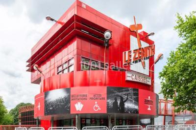 Façade vitrée avec le nom ’Le Zénith’ écrit en grandes lettres rouges sur une structure métallique.